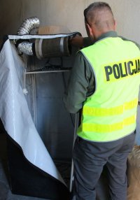 policjant wykonuje oględziny zabezpieczonego namiotu wraz z oprzyrządowaniem