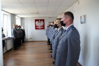 Święto Policji w Łowiczu, mianowani policjanci ustawieni w szeregu stoją w odstępach i maseczkach.