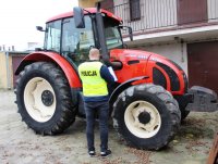 policjant wykonuje oględziny zabezpieczonego ciągnika rolniczego.