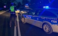 policjanci z ruchu drogowego zabezpieczają miejsce wypadku drogowego, w tle radiowóz.