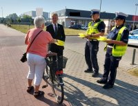 policjanci oraz burmistrz rozdają kamizelki odblaskowe.