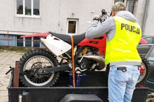 policjant w kamizelce z napisem POLICJA  wykonuje oględziny odzyskanego motocykla.