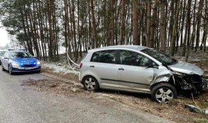 policyjny radiowóz na miejscu zdarzenia oraz rozbity samochód.