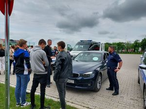 uczestnicy konferencji stoją przy samochodzie policyjnym.