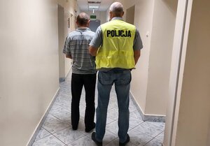 nieumundurowany policjant prowadzi zatrzymanego.