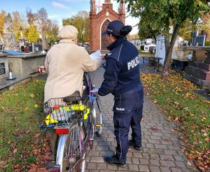 policjanci rozdają ulotki na cmentarzach.