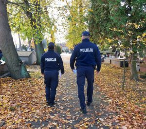 policjanci rozdają ulotki na cmentarzach.