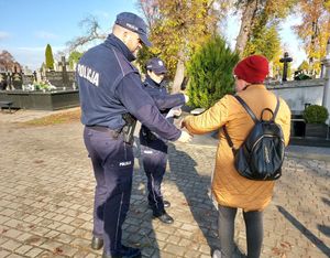 policjanci rozdają ulotki na cmentarzach.