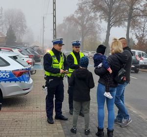 policjanci rozdają odblaski pod cmentarzami.