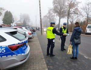 policjanci rozdają odblaski pod cmentarzami.