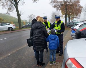 policjanci rozdają odblaski pod cmentarzami.