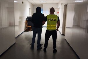 policjant prowadzi zatrzymanego.