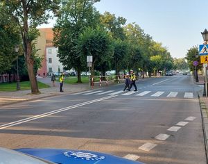 policjanci pomagają przejść na drugą stronę jezdni dzieci.