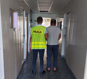 nieumundurowany policjant prowadzi zatrzymanego.