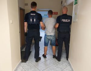 umundurowani policjanci prowadzą zatrzymanego.