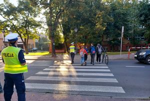 policjanci przeprowadzają dzieci przez przejście dla pieszych.