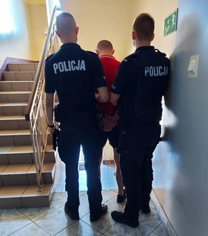 umundurowani policjanci prowadzą zatrzymanego.