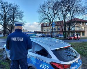 policjanci w rejonie przejazdu kolejowego wręczają kierowcom ulotki, w tle radiowóz.