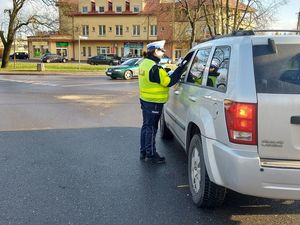 policjanci w rejonie przejazdu kolejowego wręczają kierowcom ulotki.