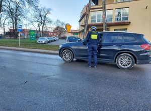 policjanci w rejonie przejazdu kolejowego wręczają kierowcom ulotki.