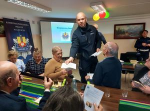 policjanci na  spotkaniu z seniorami rozdają ulotki .