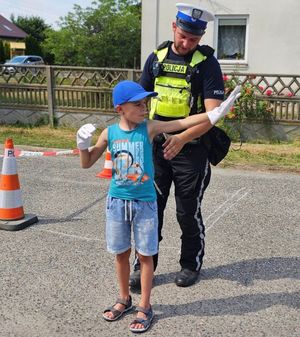 dziecko z policjantem ruchu drogowego ćwiczy kierowanie ruchem.