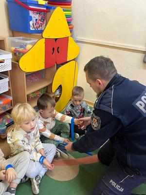 policjant rozdaje dzieciom odblaski w przedszkolu.