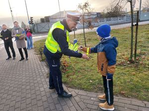 policjant wręcza odblask dziecku.