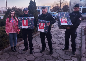 Policjanci trzymają w rękach świąteczne paczki.