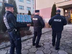 Policjanci trzymają w rękach świąteczne paczki.