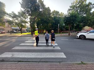 policjanci przeprowadzają przez przejście dla pieszych dzieci.