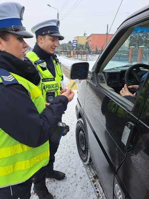 policjanci kontrolujący pojazd trzymają w ręku żółte serce z napisem zwolnij.