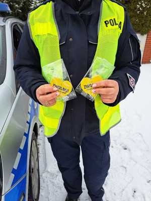 Policjantka trzymająca  żółte serce z napisem zwolnij.