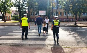 policjanci z ruchu drogowego pomagają w przejściu przez przejście dla pieszych.