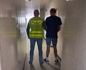nieumundurowany policjant w kamizelce z napisem POLICJA prowadzi zatrzymanego.