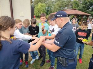 ucniowie i policjanci na pikniku policjant rozdaje odblaski.
