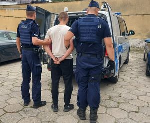 umundurowani policjanci prowadzą zatrzymanego.