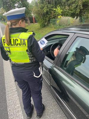 policjantka z ulotkami mistrzu zwolnij  przy kontrolowanym samochodzie.