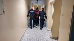 policjanci prowadzą zatrzymanego.