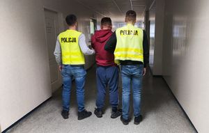 policjanci prowadzą zatrzymanego.