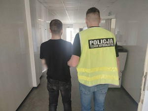 Policjant trzyma zatrzymanego.