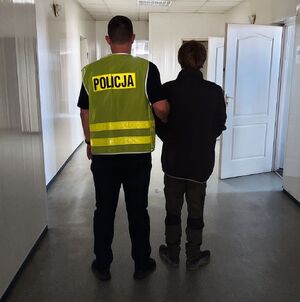 policjant prowadzi zatrzymanego.