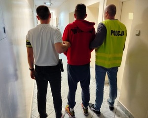 policjanci prowadzą zatrzymanego.