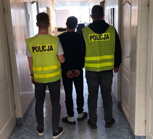 policjanci prowadzą zatrzymanego.