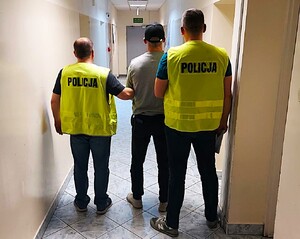 policjanci prowadzą zatrzymanego.