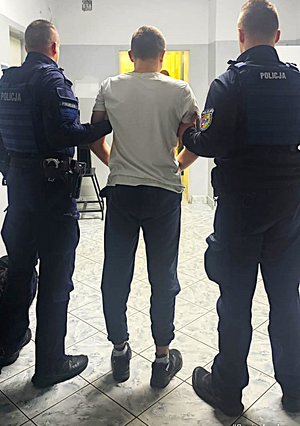 policjanci prowadzą zatrzymanego.