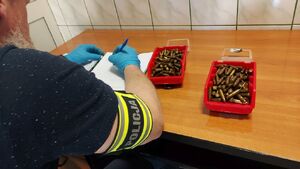 Zabezpieczona amunicja przez policjantów. Policjant wykonuje amunicję.