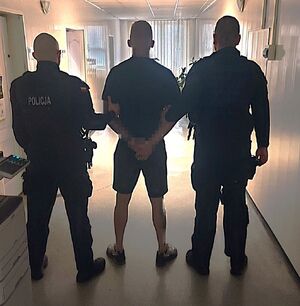 policjanci prowadzą zatrzymanego.