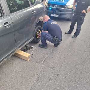 Policjant podczas wymiany koła w samochodzie.
