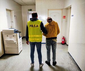 policjant prowadzi zatrzymanego.